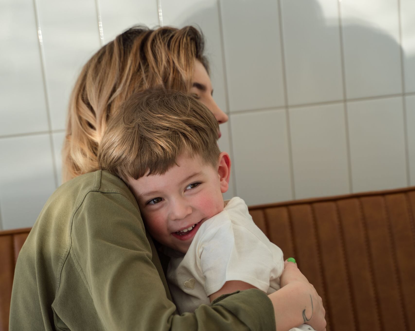 A joyful mother and son sharing a warm hug in a sunlit room, capturing a moment of love and bonding.